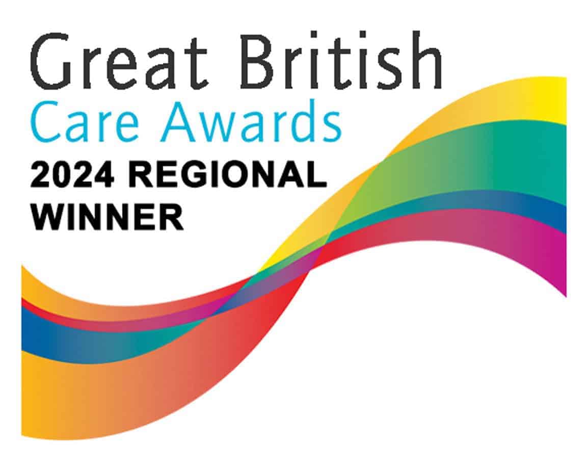 Great British Care Awards 2024 Regional Winner logo, featuring bold black and blue text above a colorful, wavy ribbon graphic in yellow, green, red, blue, and magenta on a white background.