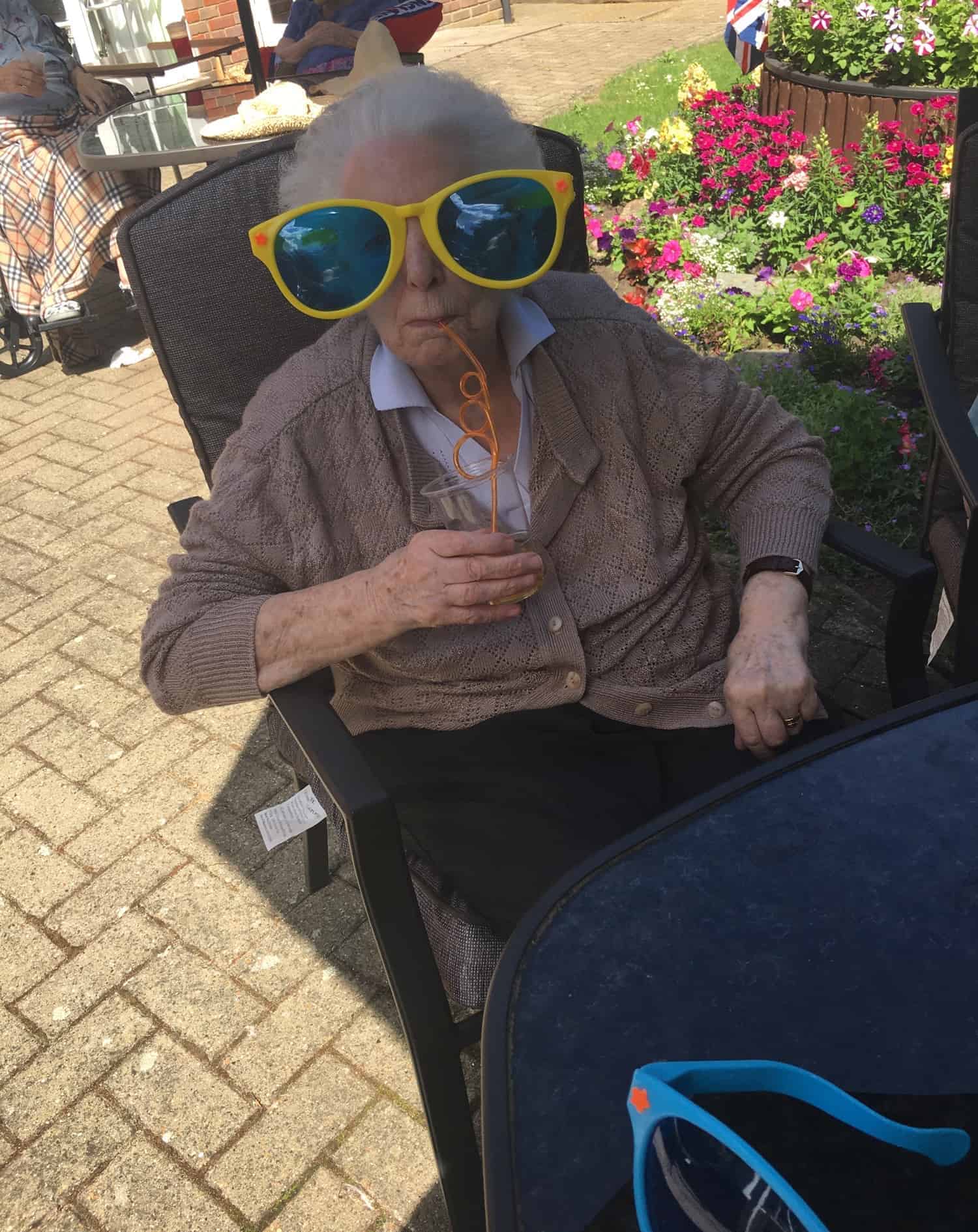 An elderly person enjoying a sunny day outdoors, sporting a pair of oversized, playful sunglasses for a fun, whimsical look at an art gallery.