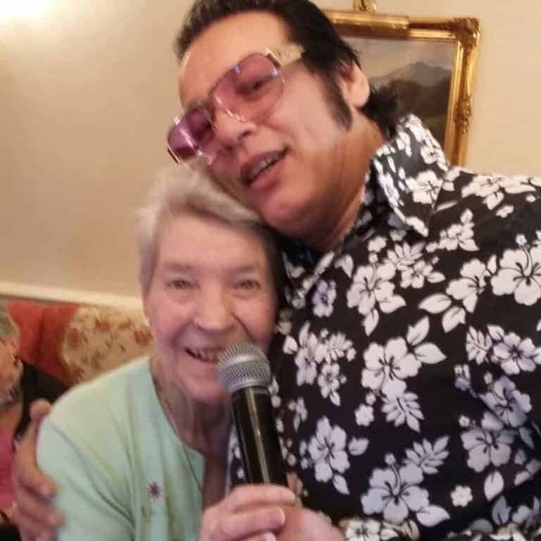 A joyful event captured as an Elvis impersonator shares a sing-along with an elderly woman, bringing a touch of nostalgia and entertainment to her day.