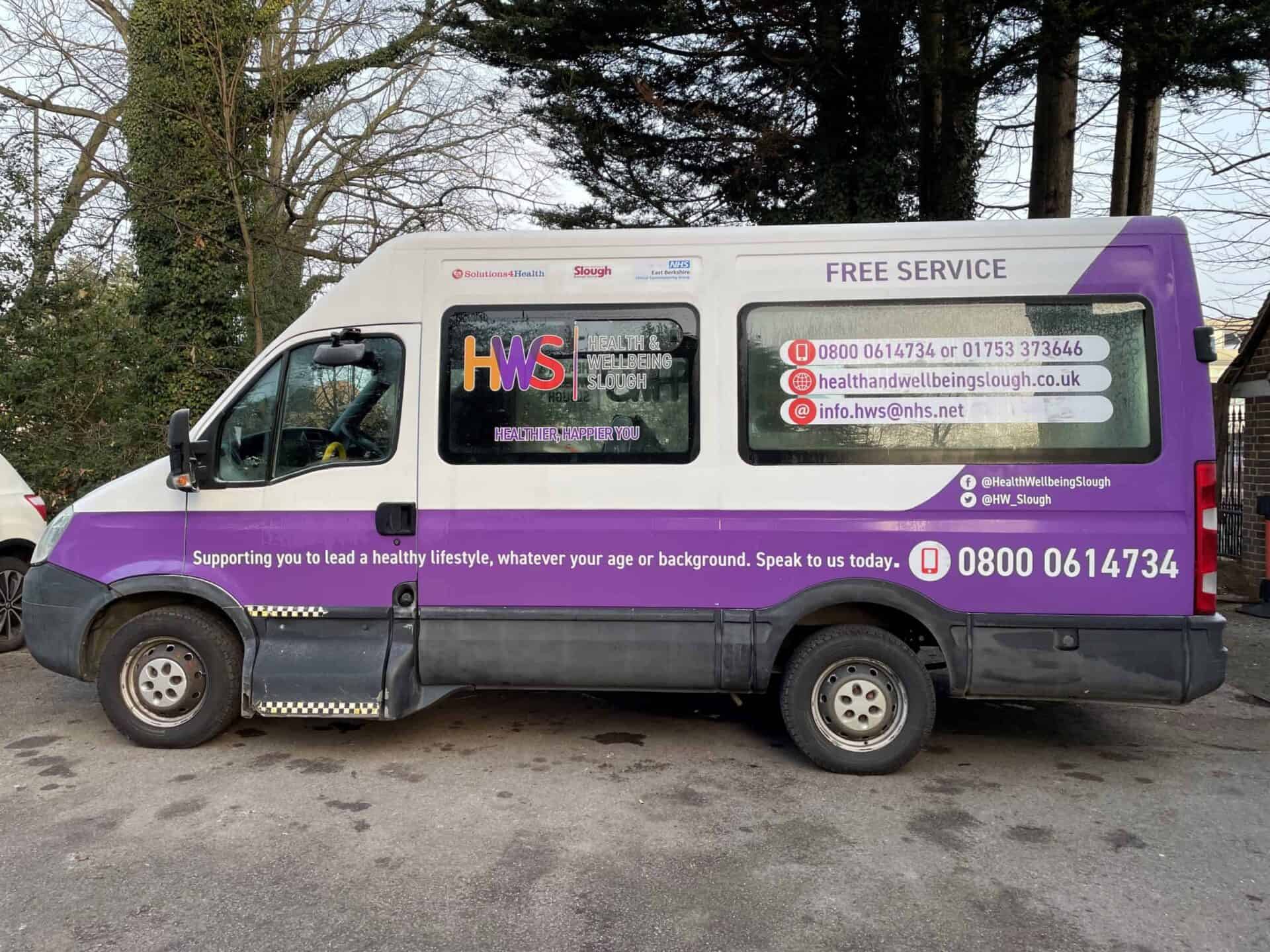 A purple and white health and wellbeing service van parked outdoors in Slough, offering free services with contact information displayed on the side.