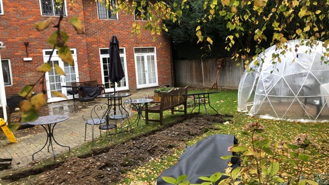 Autumn coziness in a new garden featuring a geodesic dome, inviting patio furniture, and a scattering of fallen leaves on a lush green lawn.