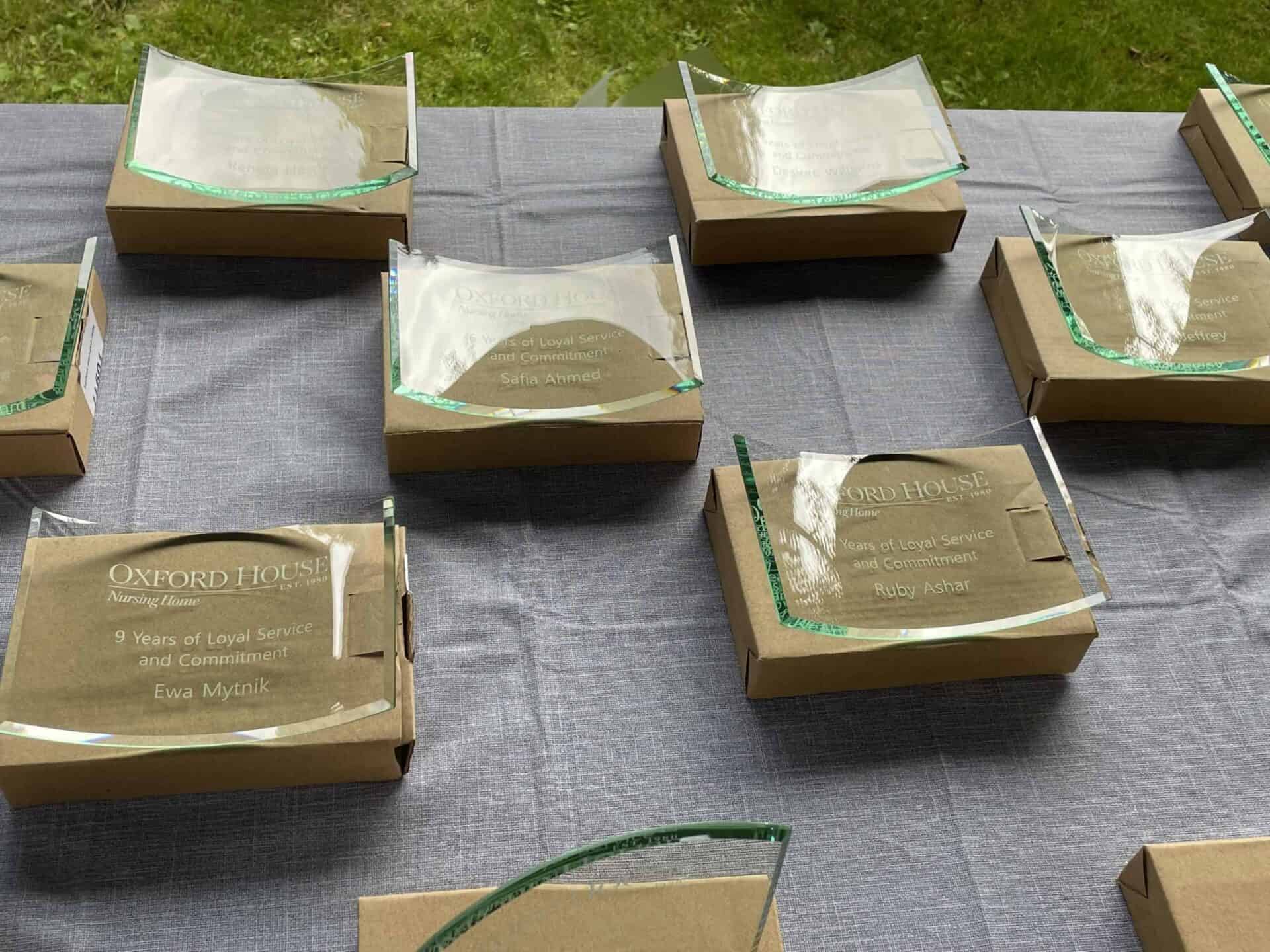 Plaques of appreciation with names displayed on a table, celebrating years of loyal service and commitment among Nursing Home Staff.