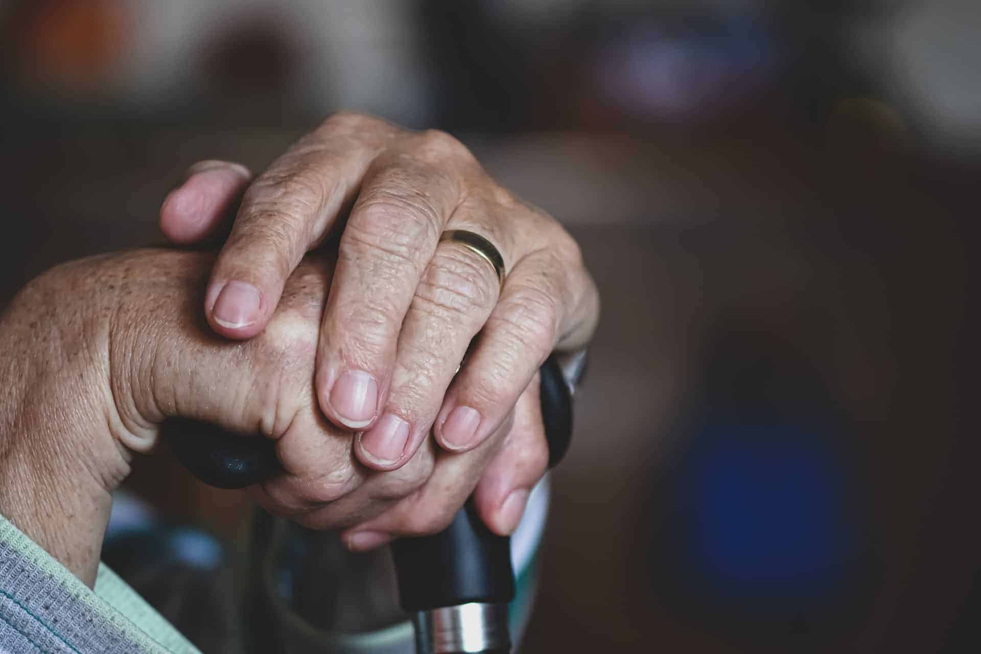 Gentle hands of elderly patients resting atop a walking cane, symbolizing the wisdom and journey of life.