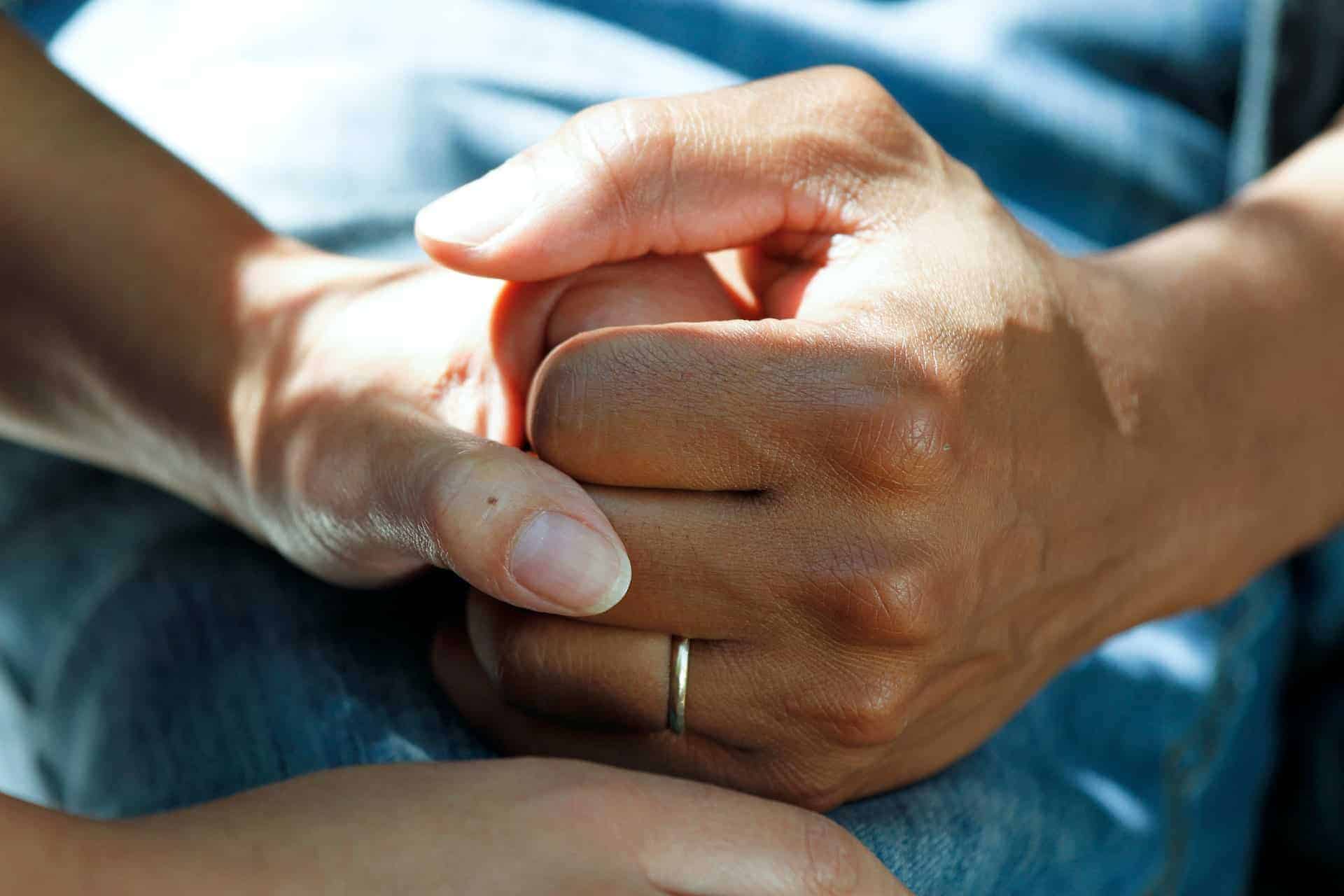 Two people in the care sector holding hands in a comforting and supportive gesture.